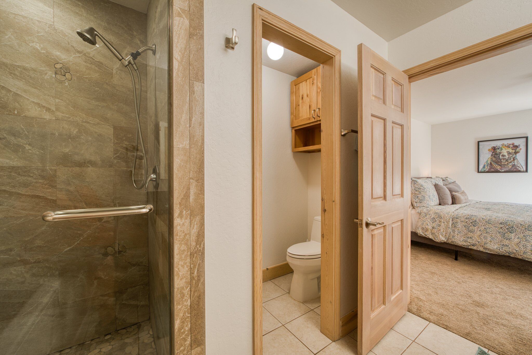 Un baño con ducha, inodoro y un mueble de madera.