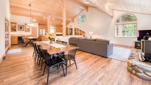 A spacious kitchen with wooden cabinets, a dining table with chairs, and a large window providing natural light.