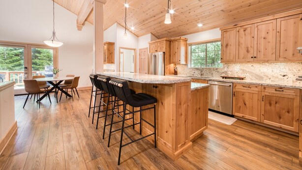 A spacious kitchen with wooden cabinets, a granite countertop, and a central island with bar stools.