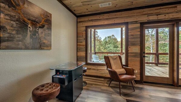 Un interior de madera con un amplio ventanal, un sillón de cuero marrón y un cuadro en la pared.