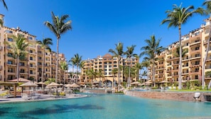 A resort with a central pool, multiple palm trees, and a large building with balconies. - Villa del Palmar Flamingos Resort & Spa (Nuevo Nayarit)