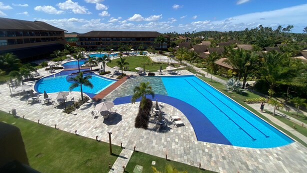 A resort with multiple swimming pools, a well-maintained lawn, and a large building in the background. - Flat 211 Vista Mar EcoResort by La Playa (Tamandaré)
