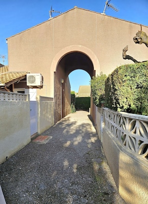 Walk through the arched entrance to our building, flanked by a low wall and decorative fence.