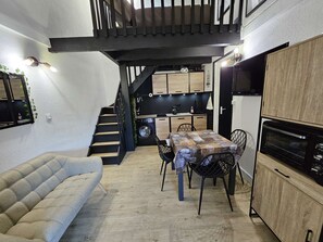 Cozy living area with a sofa, dining table for two, and a well-equipped kitchen.