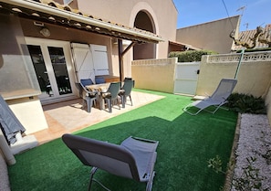 Relax in a serene outdoor space with a dining table, comfortable seating, and lush greenery.