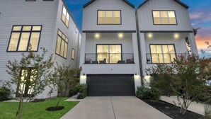 A modern two-story residential building with a garage, a balcony on the upper floor, and a well-maintained lawn. - The Houston Hangout: Modern Comfort & Style (Houston)