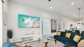 A modern living room with teal sofas, a glass coffee table, and a large abstract painting on the wall. - The Houston Hangout: Modern Comfort & Style (Houston)