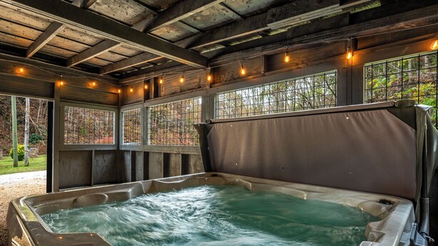 A hot tub with a control panel, surrounded by wooden beams and windows with metal grilles. - Location! ★ Game R. ★ Movie R. ★ Hot Tub ★ Fire Pit ★ King Beds ★ Dollywood! (Sevierville)