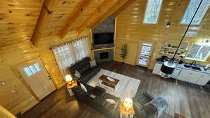 Ein geräumiger Wohnbereich mit Kamin, Holzböden und einer Küche mit Spüle und Arbeitsplatte.