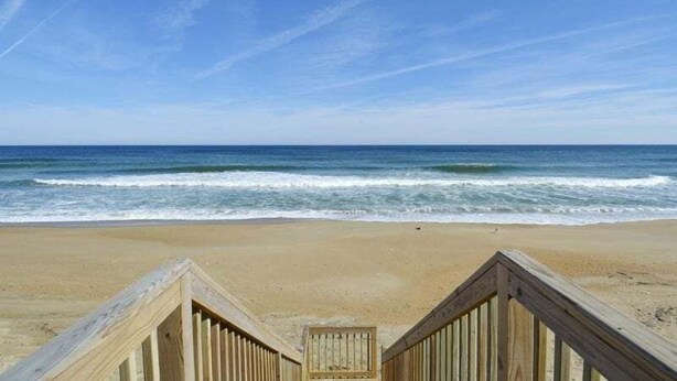 Una passerella di legno che conduce a una spiaggia con onde oceaniche.