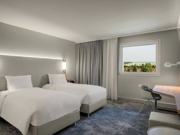 Ein Hotelzimmer mit zwei Betten, einem Schreibtisch und Blick ins Freie.