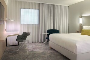 Ein Hotelzimmer mit einem Bett, einem Schreibtisch, einem Stuhl und einem kleinen Tisch.