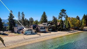 A beachfront property with multiple houses, a sandy beach, and a clear view of the water.