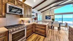 A modern kitchen with wooden cabinets, stainless steel appliances, and a view of the ocean.
