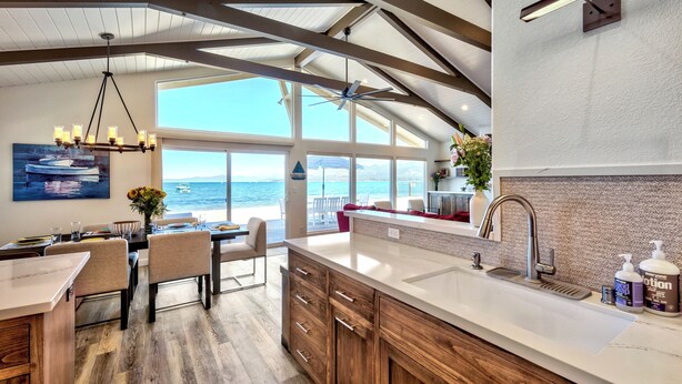 A modern kitchen with a large island, wooden cabinets, and a view of the ocean.