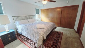 Ein Schlafzimmer mit Bett, Nachttisch, Lampe und großem Kleiderschrank.