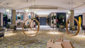 A spacious lobby with modern furniture, hanging light fixtures, and a patterned carpet.