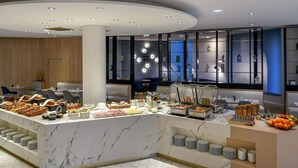 A modern breakfast bar with a marble countertop, surrounded by seating and a decorative wall with shelves.