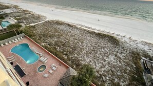 Een uitzicht op het strand met een zwembad, ligbedden en een omheind gedeelte.