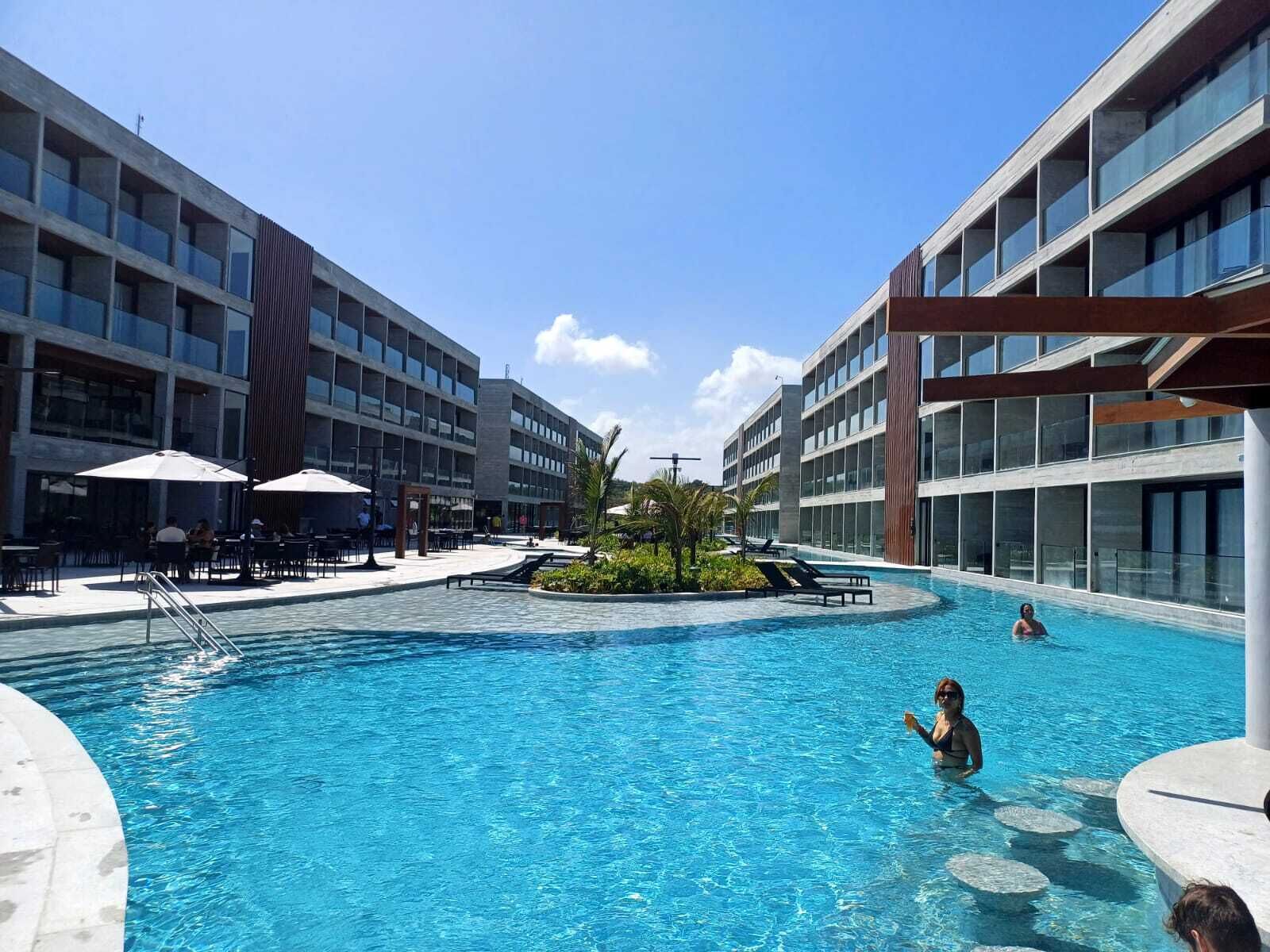 Un hôtel moderne doté d’une piscine centrale, d’un espace extérieur aménagé et d’un jardin tropical.