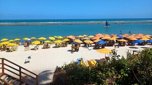 A beach with rows of yellow and orange umbrellas, a sandy area, and a clear blue sky. - Porto Alto Resort - GAV Resorts (NEAR PORTO DE GALINHA BEACH).  (Ipojuca)