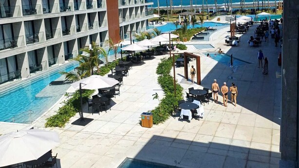 A resort pool area with multiple pools, lounge chairs, umbrellas, and a view of the ocean. - Porto Alto Resort - GAV Resorts (NEAR PORTO DE GALINHA BEACH).  (Ipojuca)