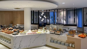 A modern breakfast bar with a marble countertop, surrounded by seating and a decorative wall with shelves.