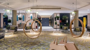 A spacious lobby with modern furniture, hanging light fixtures, and a patterned carpet.