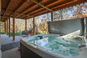 Een hottub onder een houten pergola, met uitzicht op herfstbomen.