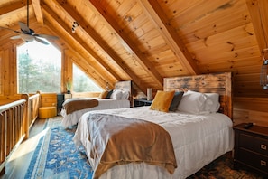 A cabin with two beds, a wooden ceiling, and a large window.