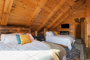 A cozy cabin with two beds, a TV, and a fireplace.
