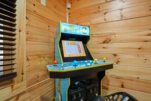A wooden-paneled room with a The Simpsons arcade game. - Byers Haven | Hocking Hills, 5BR, Hot Tub, Firepit (Logan)