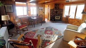 Un intérieur de chalet chaleureux comprenant un coin repas, une cheminée et un salon.