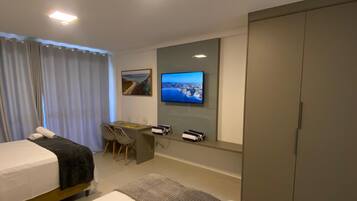 Quarto de hotel com duas camas, uma escrivaninha, televisão e guarda-roupa.