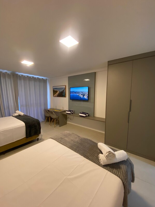 A hotel room with two beds, a desk, a television, and a wardrobe.