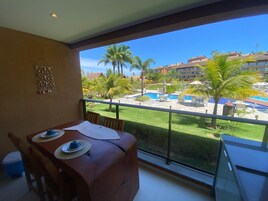 Un balcón con mesa, sillas y vistas a una piscina y edificios.