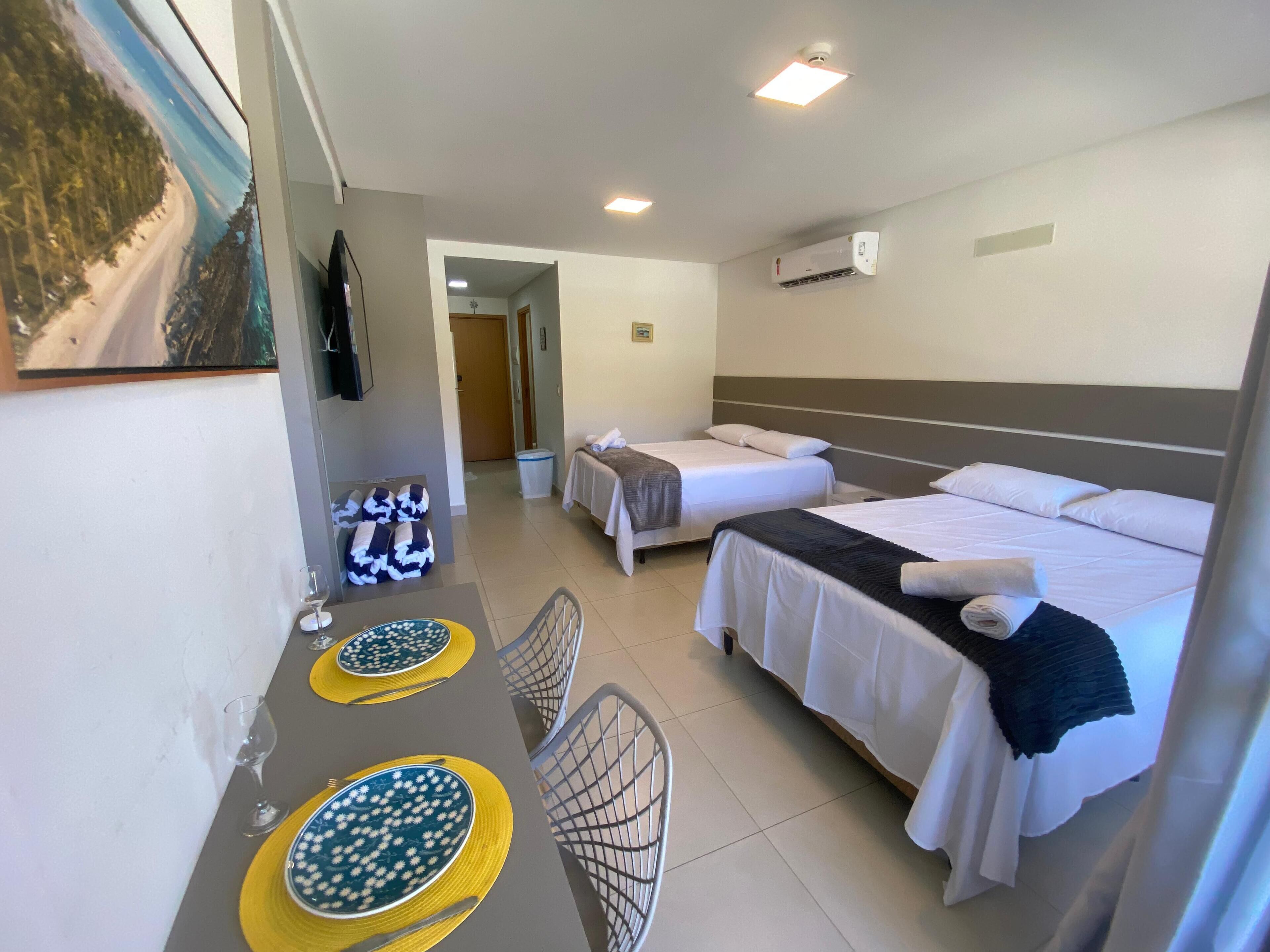 Ein Hotelzimmer mit zwei Betten, einem Esstisch mit Tellern und einem Bild an der Wand.