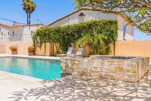 A swimming pool with a stone wall and lounge chairs. - View Park with Private Pool (View Park-Windsor Hills)
