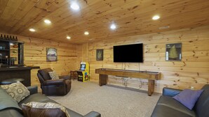 Een gezellige kamer met een pooltafel, leren fauteuils, een bar en een wandgemonteerde flatscreen-tv.