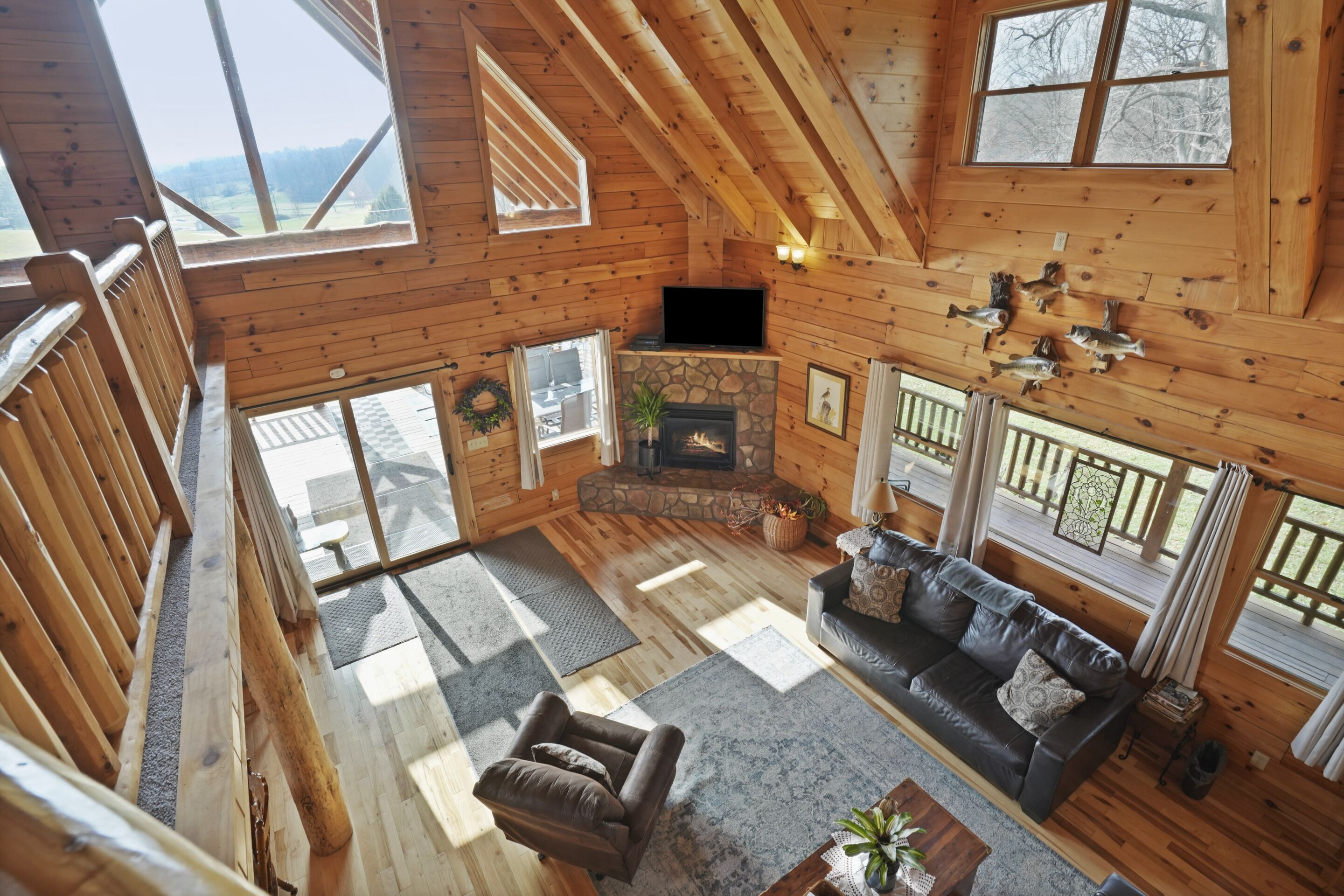 Una cabaña espaciosa de madera con chimenea de piedra, sofá de cuero y televisor.