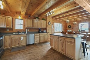 A spacious kitchen with wooden cabinets, a central island, and a dining area with chairs.