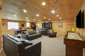 Ein gemütliches Blockhauss-Interieur mit einem Wohnzimmer, das eine Couch, Sessel, eine Bar und einen Billardtisch bietet.