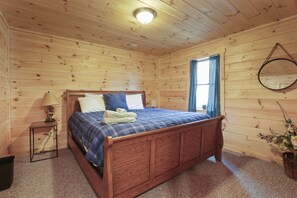 A wooden-paneled bedroom with a bed, a nightstand, a lamp, and a mirror.