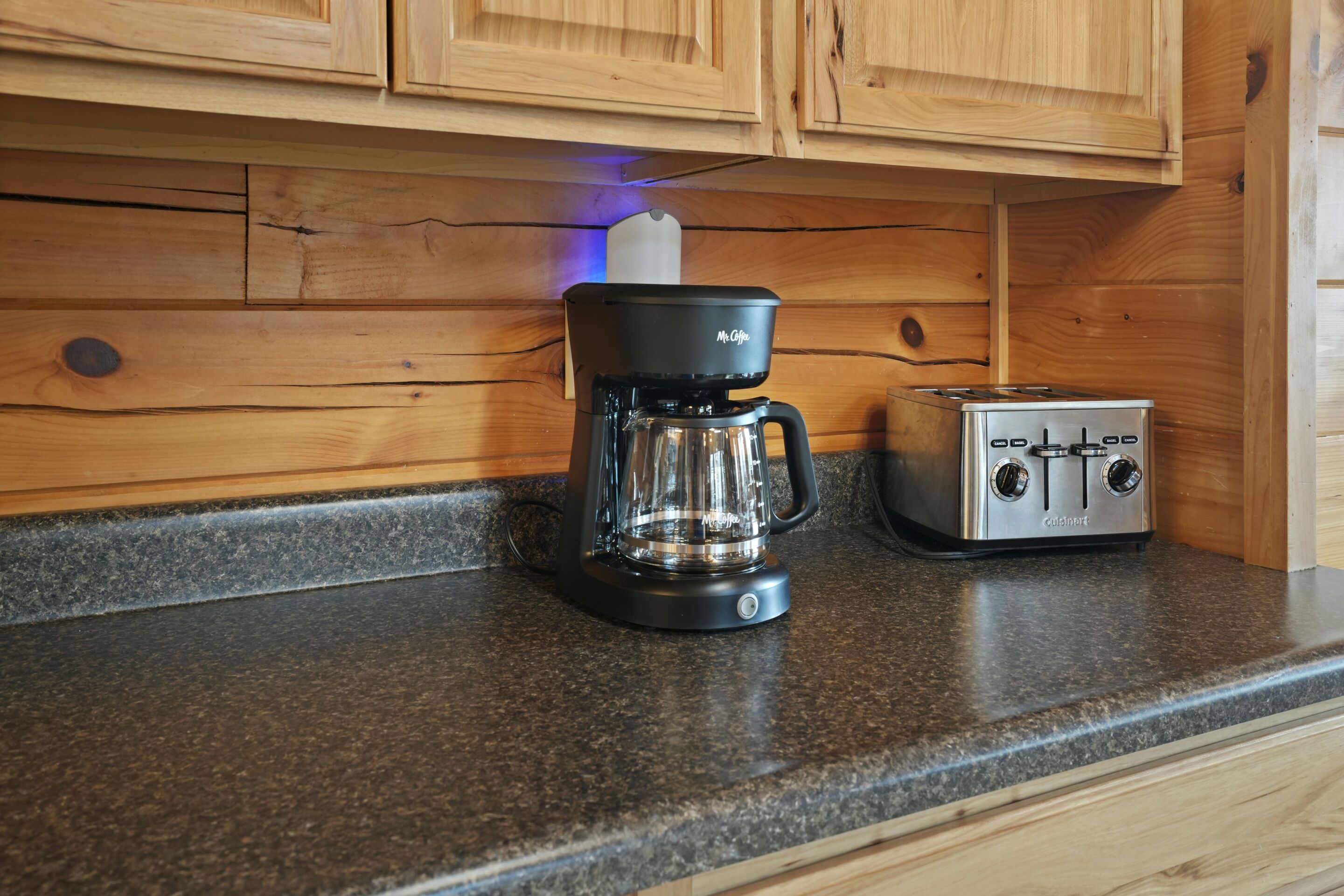 A kitchen with wooden cabinets, a coffee maker, and a toaster on the countertop.