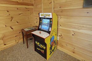 A Pac-Man arcade game in a room with wooden walls and a small table.