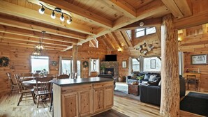Een ruim houten vakantiehuis aan de binnenkant, met een ruime eethoek, keuken en woonkamer.