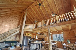 A spacious cabin interior with a wooden interior, a dining area, a kitchen, and a balcony.