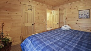 Een kamer met houten lambrisering, een bed, een deur en een lijst met een afbeelding aan de muur.