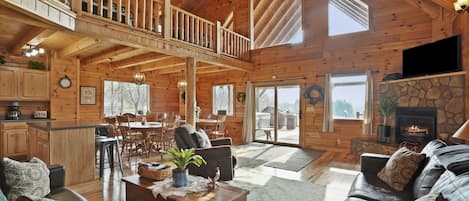 A spacious log cabin interior with a dining area, living room, and a fireplace.