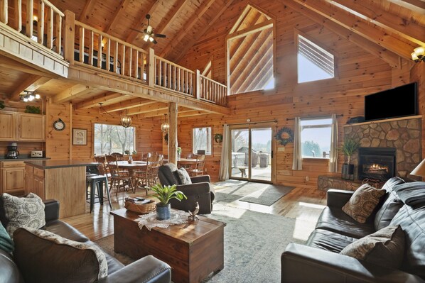 A spacious log cabin interior with a dining area, living room, and a fireplace. - MeadowLark Lodge | Hocking Hills, Sleeps 20, Views (Logan)